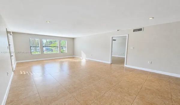 Spacious room featuring neutral wall tones, large-format tile flooring, recessed ceiling lighting, and multiple windows