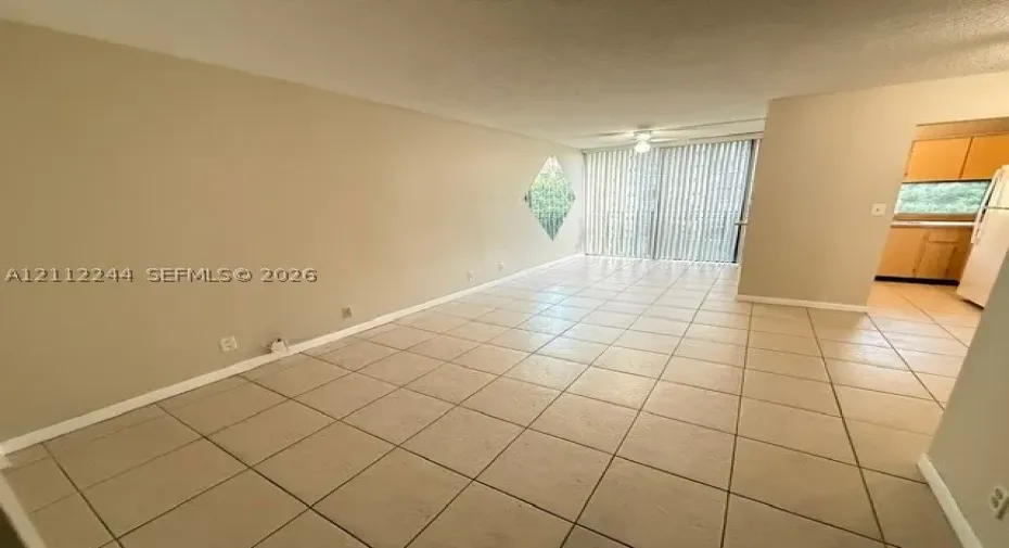 Neutral tile flooring, diamond-shaped accent window, and sliding glass door with vertical blinds
