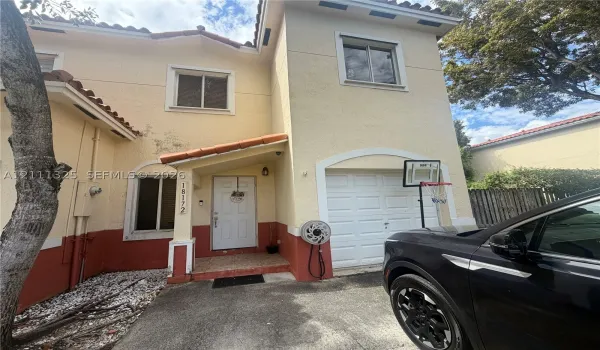 Two-story exterior featuring a stucco façade, tile roof accents, covered entryway, and an attached one-car garage