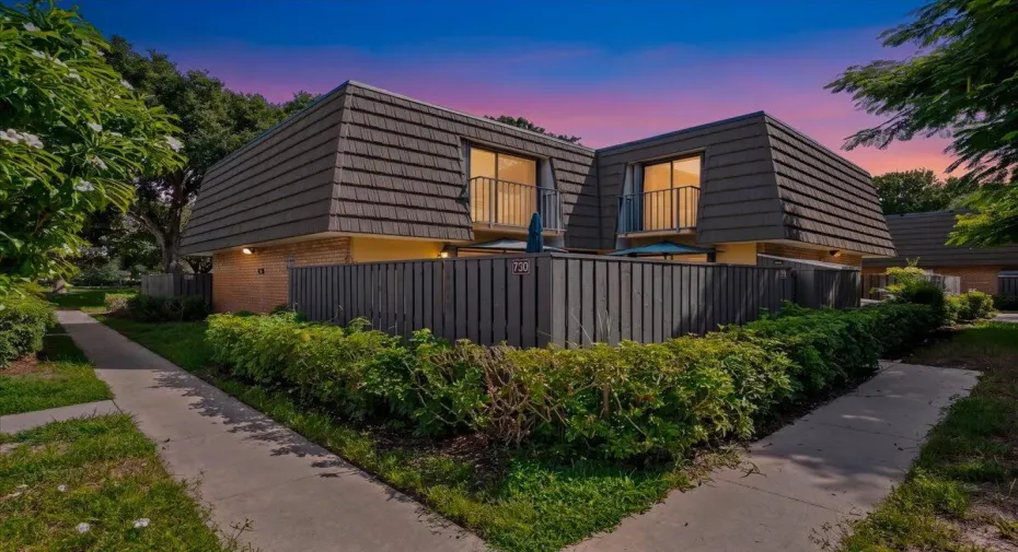 Welcome Home. A charming courtyard-style residence surrounded by mature landscaping and a private outdoor setting.