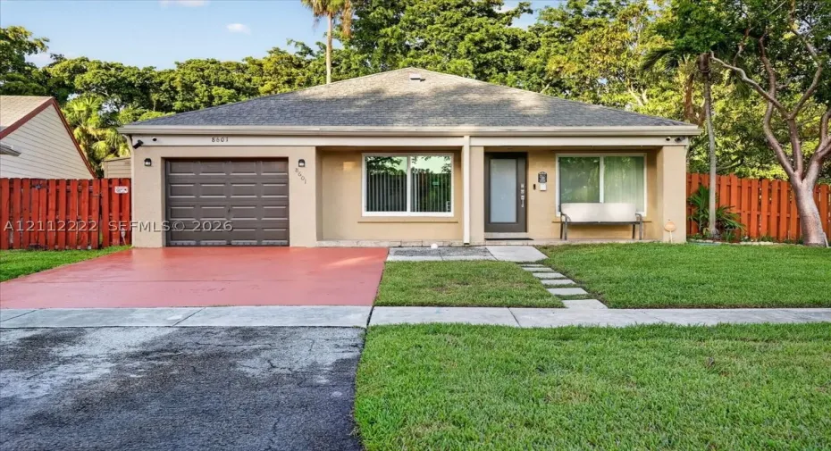 Single-story residence featuring a shingled roof, attached one-car garage, painted stucco exterior, glass-panel entry door, and perimeter privacy fencing