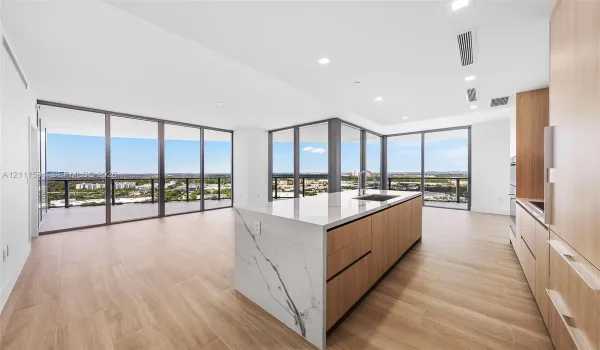 Kitchen featuring wood-finish cabinetry, an island with a stone-surface countertop, floor-to-ceiling glass panel walls, and wood-finish flooring