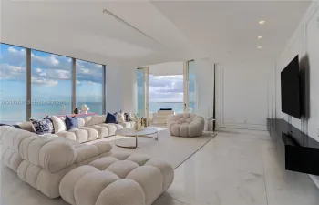 Floor-to-ceiling windows, polished stone flooring, recessed ceiling lighting, wall panel molding, and sliding glass doors to the exterior