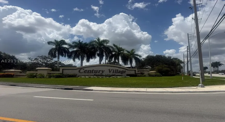 Community monument signage featuring masonry construction, integrated landscaping, and mature palm trees