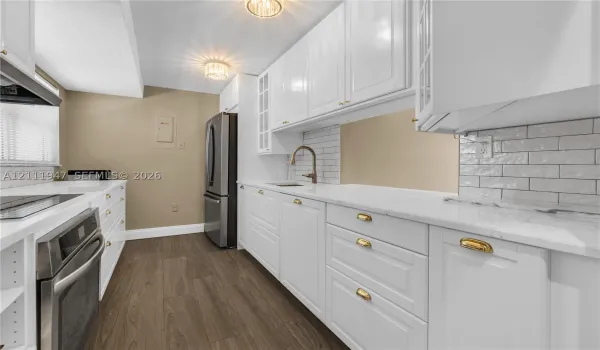 Kitchen featuring white shaker cabinetry, stone-finish countertops, subway tile backsplash, stainless steel appliances, and wood-finish flooring