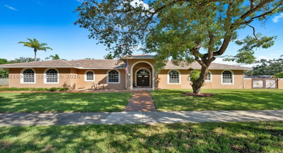 Single-story exterior featuring a stamped concrete walkway, arched entryway, and multiple arched windows * concrete wall in the front with custom metal gates *