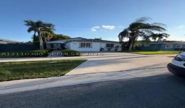 Single-story exterior featuring white stucco siding, a tiled roof, multi-pane windows, and a concrete driveway