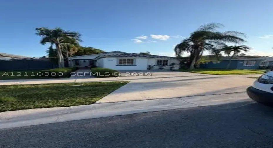 Single-story exterior featuring white stucco siding, a tiled roof, multi-pane windows, and a concrete driveway