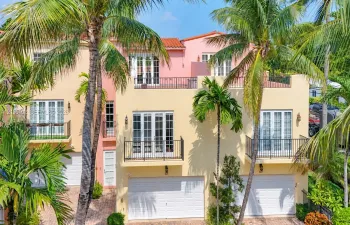 Mediterranean-inspired multi-level exterior featuring clay tile roofing, stucco facade, multiple private balconies with metal railings, and dual garage access
