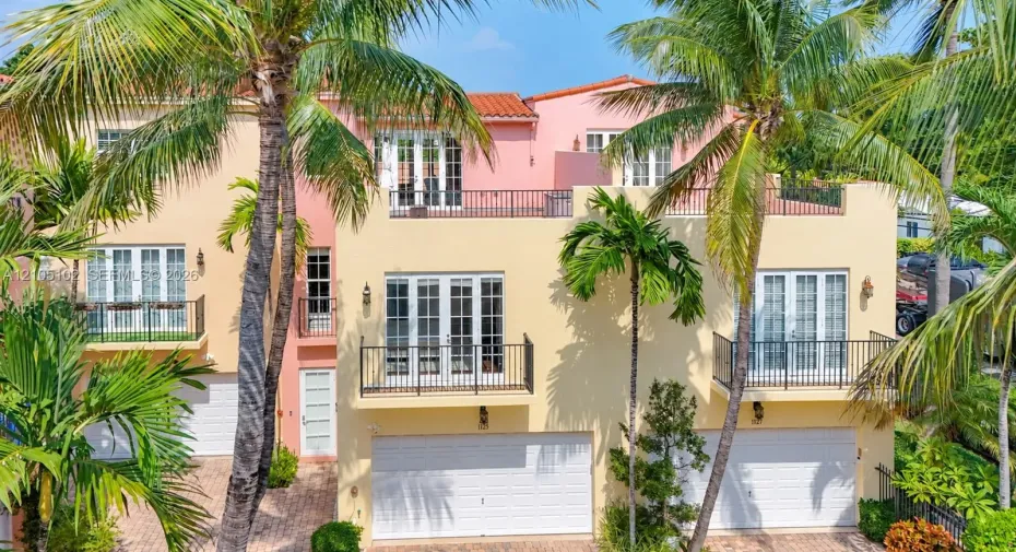 Mediterranean-inspired multi-level exterior featuring clay tile roofing, stucco facade, multiple private balconies with metal railings, and dual garage access
