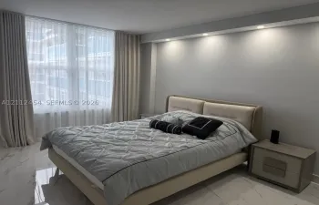Floor-to-ceiling windows with floor-length drapery, recessed ceiling lighting, and polished stone-finish flooring