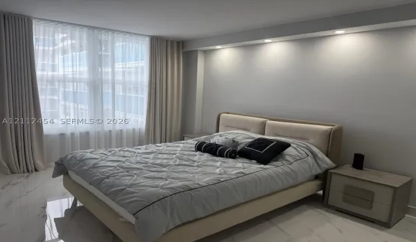 Floor-to-ceiling windows with floor-length drapery, recessed ceiling lighting, and polished stone-finish flooring
