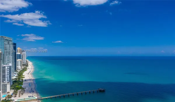 Coastal aerial perspective featuring expansive ocean scenery, a shoreline, and a pier