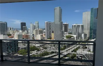 Private balcony featuring a dark metal mesh railing and tile flooring overlooking a cityscape
