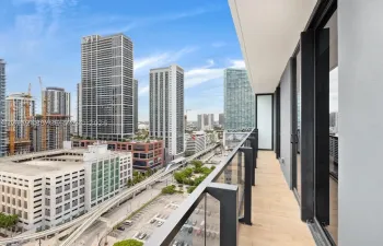 Covered balcony featuring wood-finish flooring, glass panel railings, and metal structural framing
