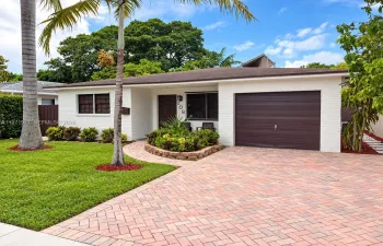 Single-story residence featuring a painted brick exterior, an attached one-car garage with a horizontal-panel door, and a herringbone-patterned paved driveway
