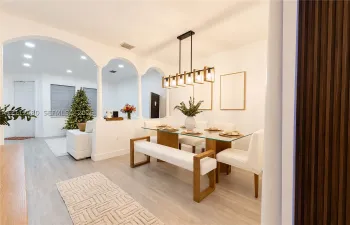 Dining area featuring arched wall openings supported by columns, wood-finish flooring, a linear multi-light metal chandelier, and a vertical wood slat wall accent
