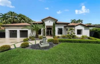 Single-story residence featuring a tile roof, stucco exterior, two-car garage, stone water fountain, and manicured landscaping
