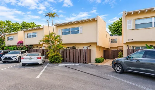 Stucco exterior featuring exposed rafter tails, horizontal wood fencing, and designated parking space