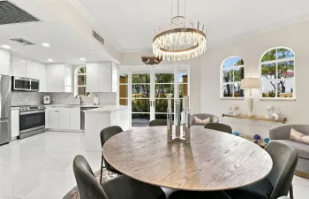 Kitchen and dining area featuring high-gloss cabinetry, stainless steel appliances, polished stone-finish flooring, a contemporary drum chandelier, and arched windows