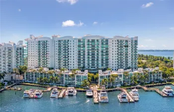 Multi-story residential complex featuring private boat slips, deep-water dockage, glass-railed balconies, and extensive perimeter landscaping