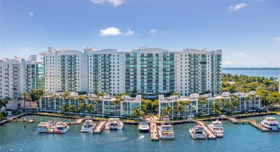 Multi-story residential complex featuring private boat slips, deep-water dockage, glass-railed balconies, and extensive perimeter landscaping
