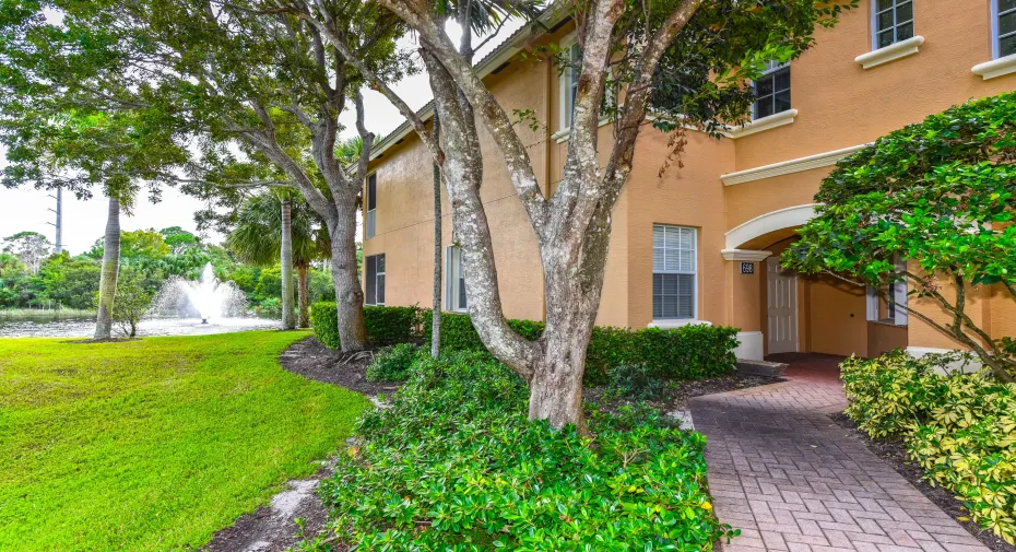 Arched entryway, sotne-paver walkway, manicured shrubbery and landscaped pond with a fountain