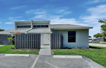 Exterior facade featuring a flat roofline, clerestory windows, stucco siding, and a private wooden privacy fence