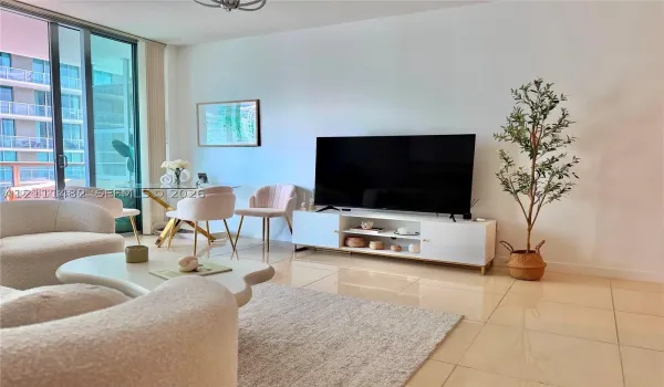 Open-concept interior featuring large-format tile flooring, full-height sliding glass doors, and a neutral color palette