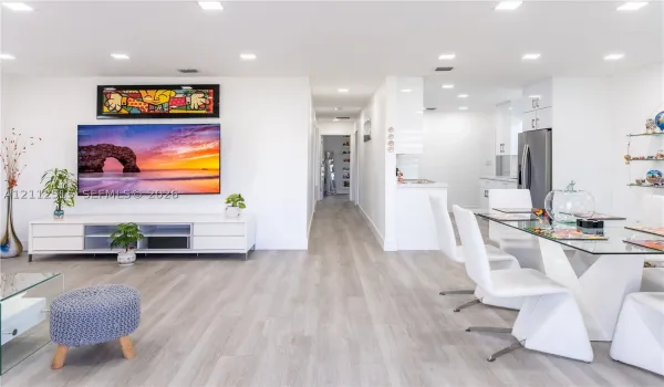 Open-concept interior featuring light wood-finish flooring, recessed ceiling lighting, and crisp white walls throughout