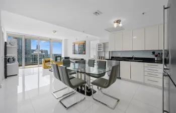 Open-concept kitchen featuring high-gloss cabinetry, dark stone countertops, and stainless steel appliances
