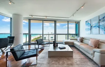 Floor-to-ceiling glass windows, wood-finish flooring, recessed track lighting, and a private balcony