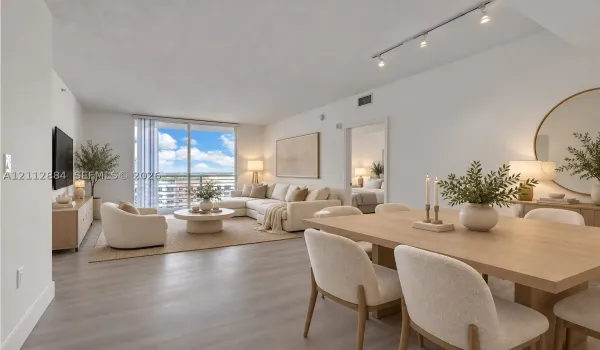 Open-concept living space featuring wood-finish flooring, sliding glass balcony doors, and adjustable track lighting