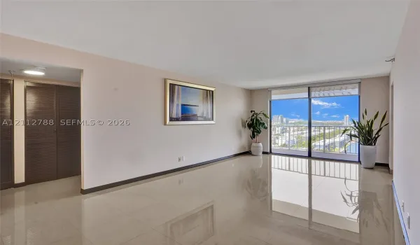 Living area featuring polished tile flooring, floor-to-ceiling glass sliding doors, a metal balcony railing, and built-in louvered closet doors