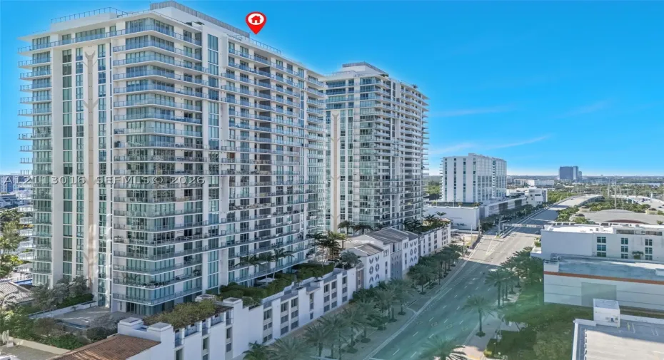 High-rise architectural structure featuring glass-paneled balconies, floor-to-ceiling windows, and rooftop terracing