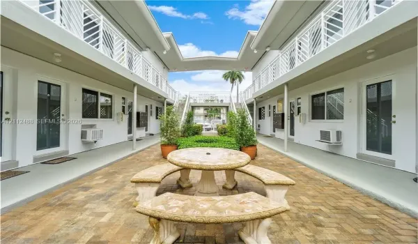 Courtyard area featuring brick paver flooring, stone masonry seating, metal lattice railings, and exterior walkways