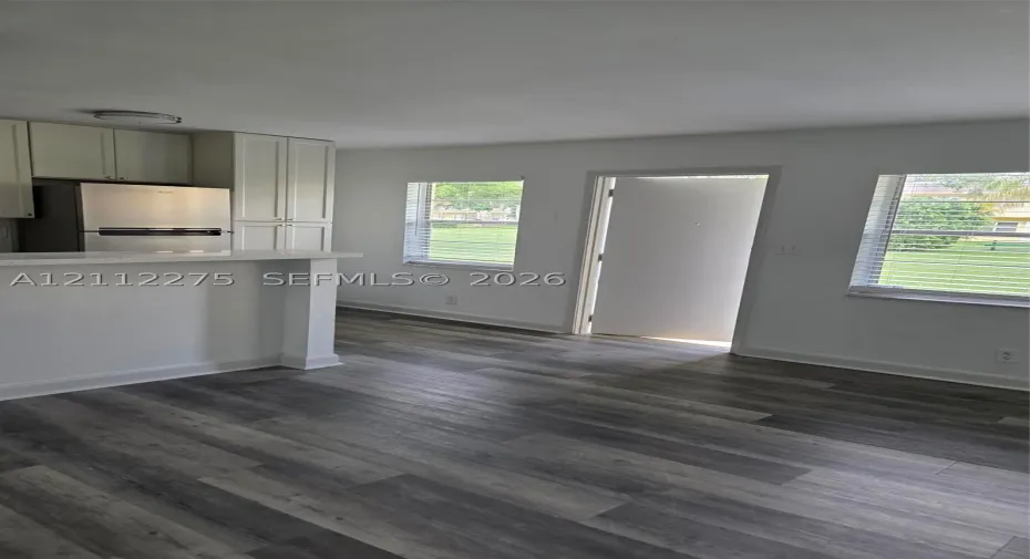 Kitchen featuring light-toned cabinetry, stainless steel appliances, a peninsula breakfast bar with light-toned countertop, and wood-finish flooring throughout