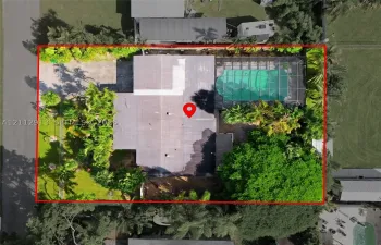 Aerial perspective featuring a screen-enclosed pool, paved driveway, and mature landscaping