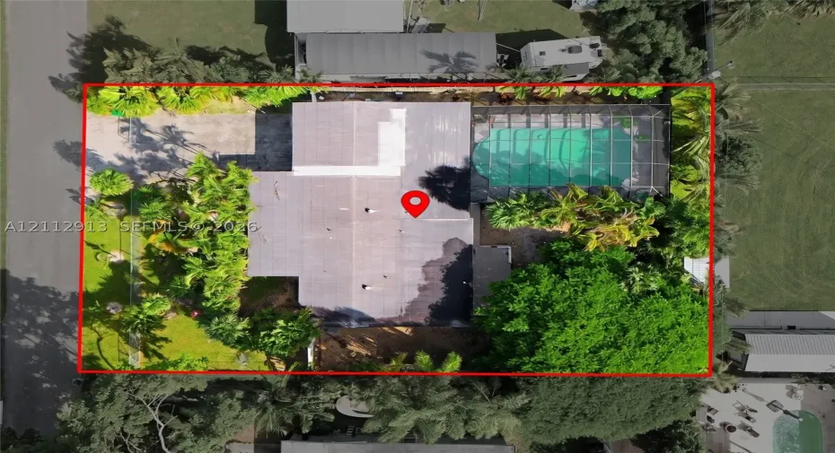 Aerial perspective featuring a screen-enclosed pool, paved driveway, and mature landscaping