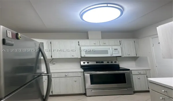 Kitchen featuring light-finish cabinetry, stainless steel refrigerator and range, over-the-range microwave, and overhead flush-mount lighting