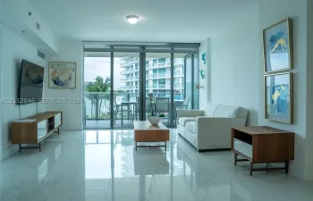 Large-format polished stone flooring, floor-to-ceiling glass sliding doors, and a private balcony with glass railing