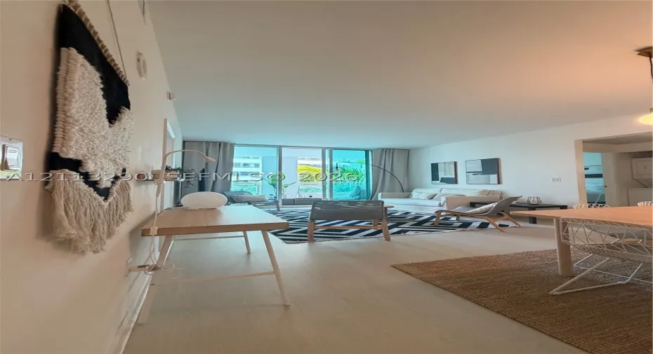 Open-concept interior featuring wood-finish flooring, high ceilings, and floor-to-ceiling glass doors providing access to a balcony