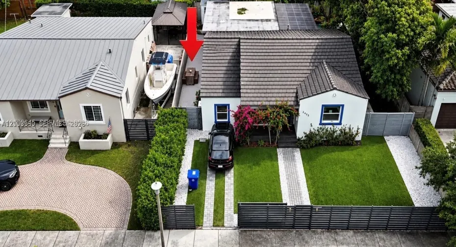 Single-story residence featuring a tile roof, gated front entry, paver driveway, manicured lawn, and hardscaped side patio