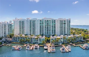 Multi-story residential complex featuring private boat slips, deep-water dockage, glass-railed balconies, and extensive perimeter landscaping