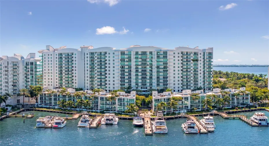 Multi-story residential complex featuring private boat slips, deep-water dockage, glass-railed balconies, and extensive perimeter landscaping