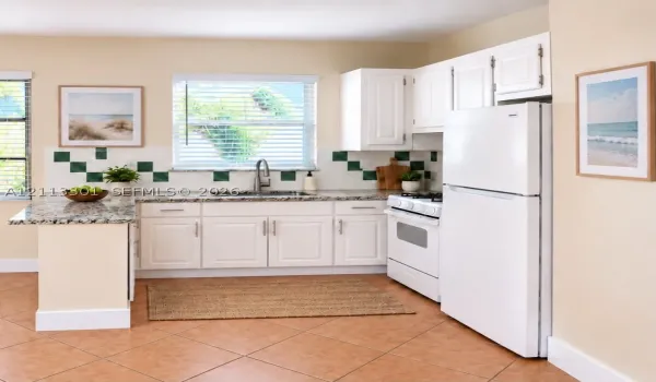 Kitchen featuring white shaker-style cabinetry, stone-finish countertops, decorative tile backsplash, stainless steel sink with pull-down faucet, and neutral tile flooring