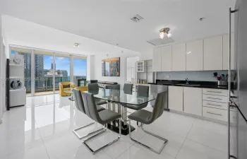 Open-concept kitchen featuring high-gloss cabinetry, dark stone countertops, and stainless steel appliances