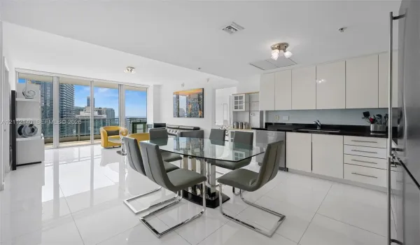 Open-concept kitchen featuring high-gloss cabinetry, dark stone countertops, and stainless steel appliances