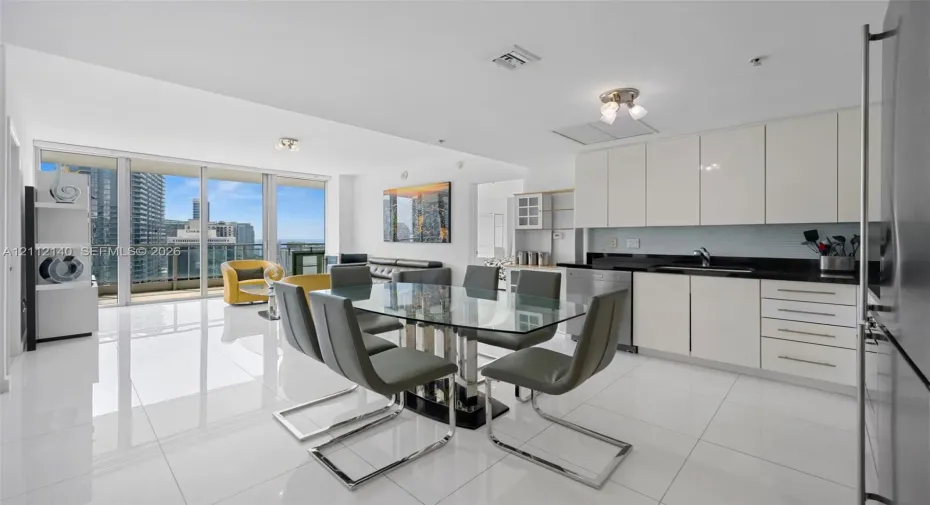 Open-concept kitchen featuring high-gloss cabinetry, dark stone countertops, and stainless steel appliances