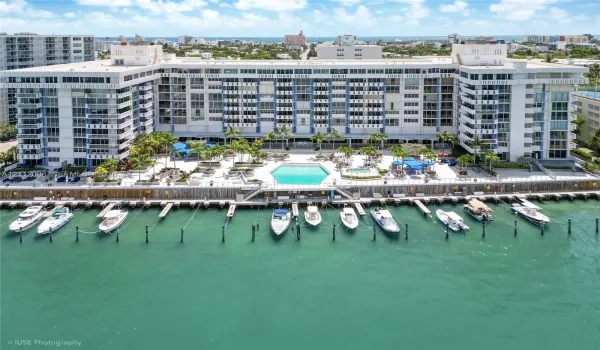 Waterfront multi-story residential building featuring a private deep-water dock, integrated swimming pool, spa, and exterior balcony access for residential units